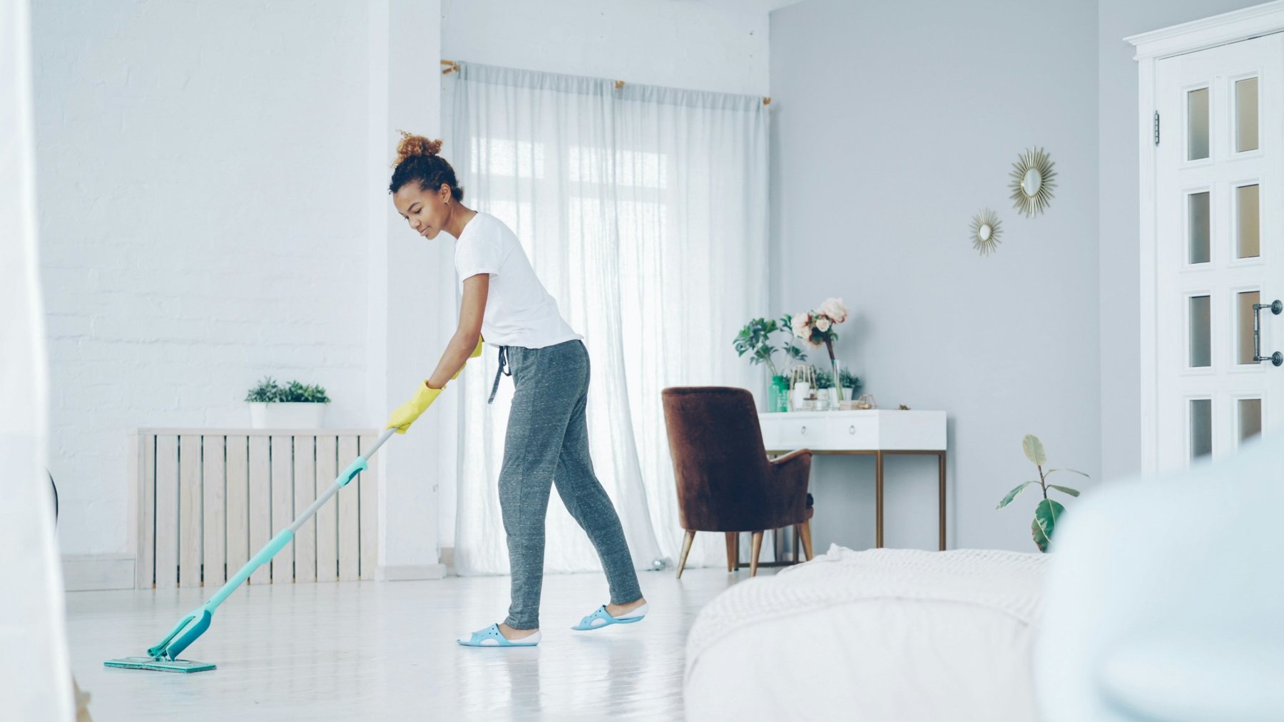 A cleaner mopping a bright bedroom floor